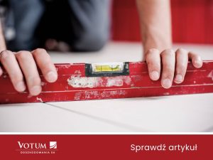 Mężczyzna sprawdza poziomicą podłogę - jest krzywa. Moze to być powód do odszkodowania za szkody górnicze.
