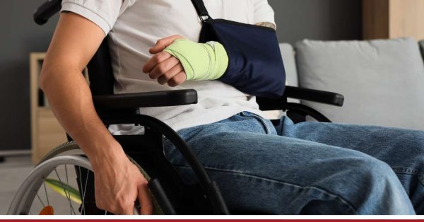 osoba na wózku inwalidzkim i z ręką na temblaku po wypadku - renta po wypadku