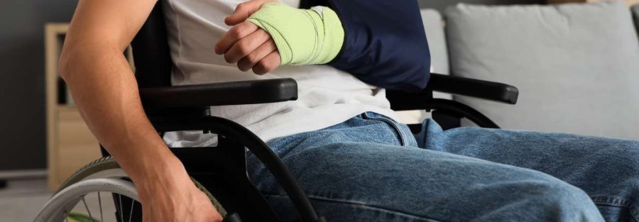 osoba na wózku inwalidzkim i z ręką na temblaku po wypadku - renta po wypadku